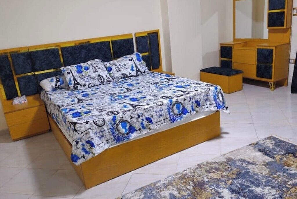 Une chambre à coucher comprenant un lit, des tables de chevet, une commode et un miroir.