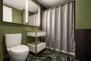 Een badkamer met toilet, wastafel met spiegel en douchegordijn.
