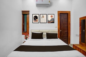 Une chambre à coucher comprenant un lit, un climatiseur fixé au mur et trois œuvres d’art encadrées.