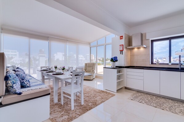A modern kitchen with white cabinets, a black countertop, and a large window. - Carteia Beachfront at Praia da Gaivota (Loulé)