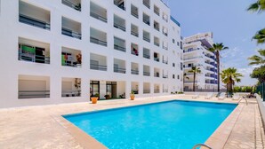 A hotel with a swimming pool, multiple balconies, and palm trees. - Carteia Beachfront at Praia da Gaivota (Loulé)