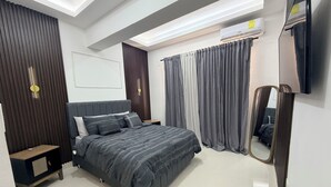 Un dormitorio moderno con cama, mesita de noche, cortinas y un aire acondicionado.