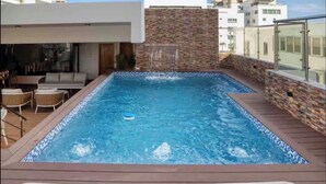 Una piscina rectangular con un muro de piedra y una cubierta de madera.