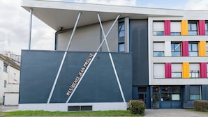 Ein modernes Gebäude mit flachem Dach und großem Eingang, mit einem Schild, auf dem "RESIDENCE JEANFORLE" steht.