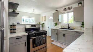 A modern kitchen with grey cabinets, a stainless steel stove, and a window with a view.