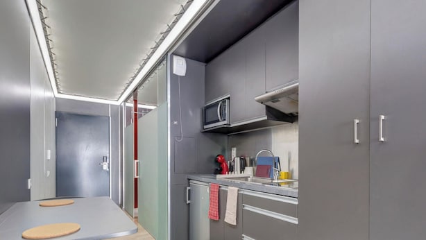 A compact kitchen with grey cabinets, a microwave, a sink, and a small countertop. - 05 - Le Lokup - Wifi - Proche tram (Reims)