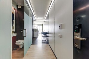 En moderne gang med toilet, vask og en dør med kode lås.