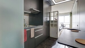 A modern kitchen with grey cabinets, a stainless steel range hood, a countertop with a sink, and a dining area with a table and chairs. - 30 - Le Lokup - Wifi - Proche tram (Reims)