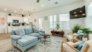 A modern living room with a light blue sectional sofa, a coffee table, and a TV mounted on the wall. - Stunning Surfside Beach House Near The Jetty (Surfside Beach)