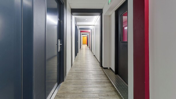 Un pasillo largo y estrecho con puertas a ambos lados, que da acceso a habitaciones.