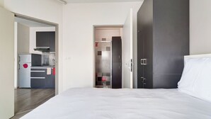 Un dormitorio con una cama grande, un armario y una kitchenette en la habitación contigua.
