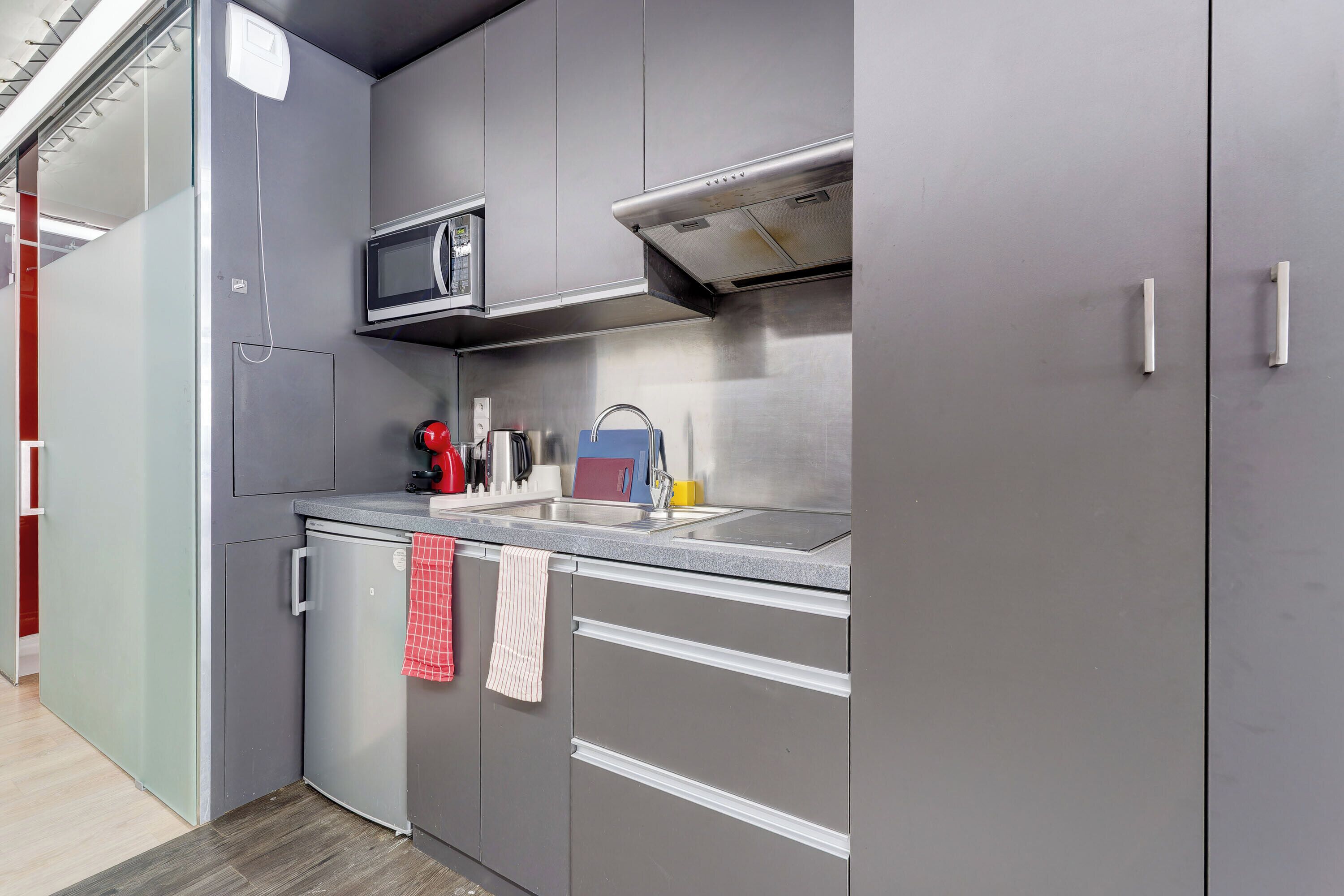 A modern kitchen with grey cabinets, a stainless steel microwave, and a built-in oven.