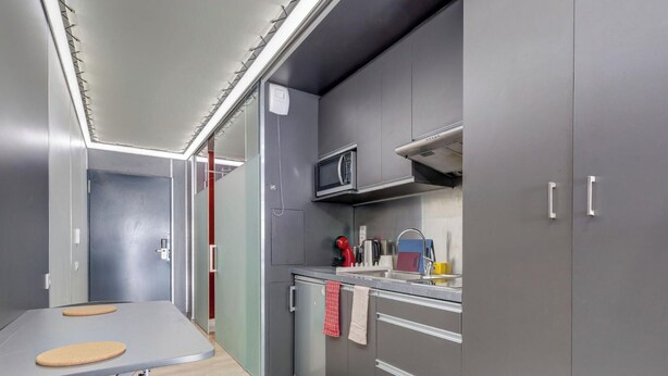 Una cocina compacta con armarios grises, un microondas, un lavabo y una pequeña encimera.