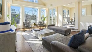 A spacious living room with a high ceiling, skylights, and large windows offering views of the outdoors. - Luxury Mansion available with Pool, Gym and More - Perfect for entertaining (Atlanta)