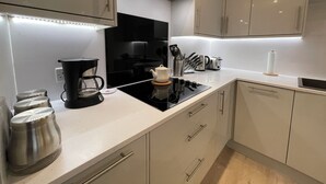 Een moderne keuken met witte kasten, een zwart fornuis en roestvrijstalen apparatuur.