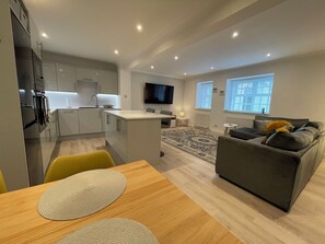 A modern apartment with a kitchen, dining area, living room, and a TV mounted on the wall. - 1 The Maltings, village centre 2 bed 2 bath ground floor apartment, ideal base (Crail)
