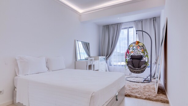 A modern bedroom with a large bed, a desk, and a hanging chair. - Carteia Beachfront at Praia da Gaivota (Loulé)