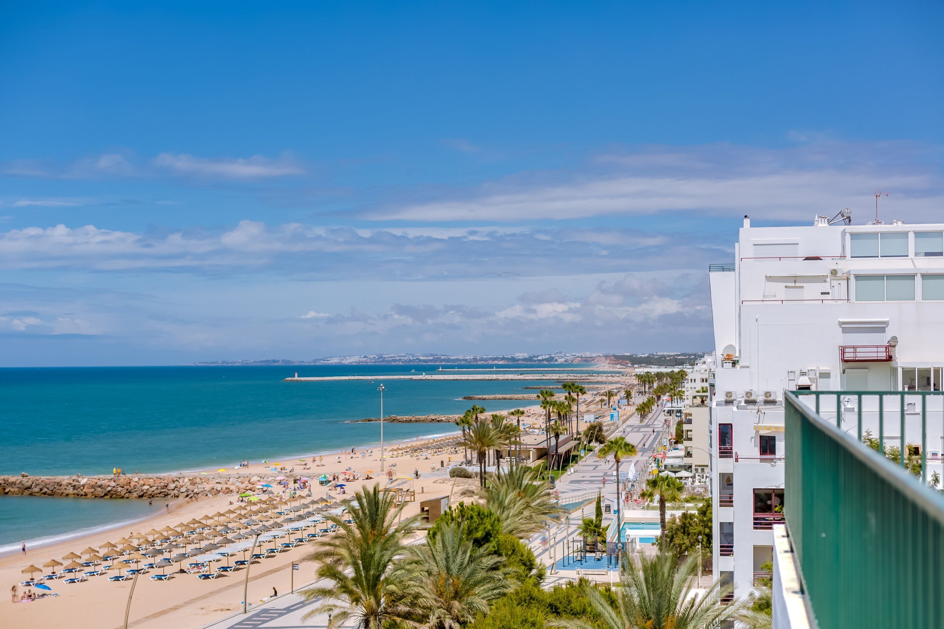 Ein Hotel direkt am Strand mit Blick auf das Meer und einem Felsenmole in der Ferne.