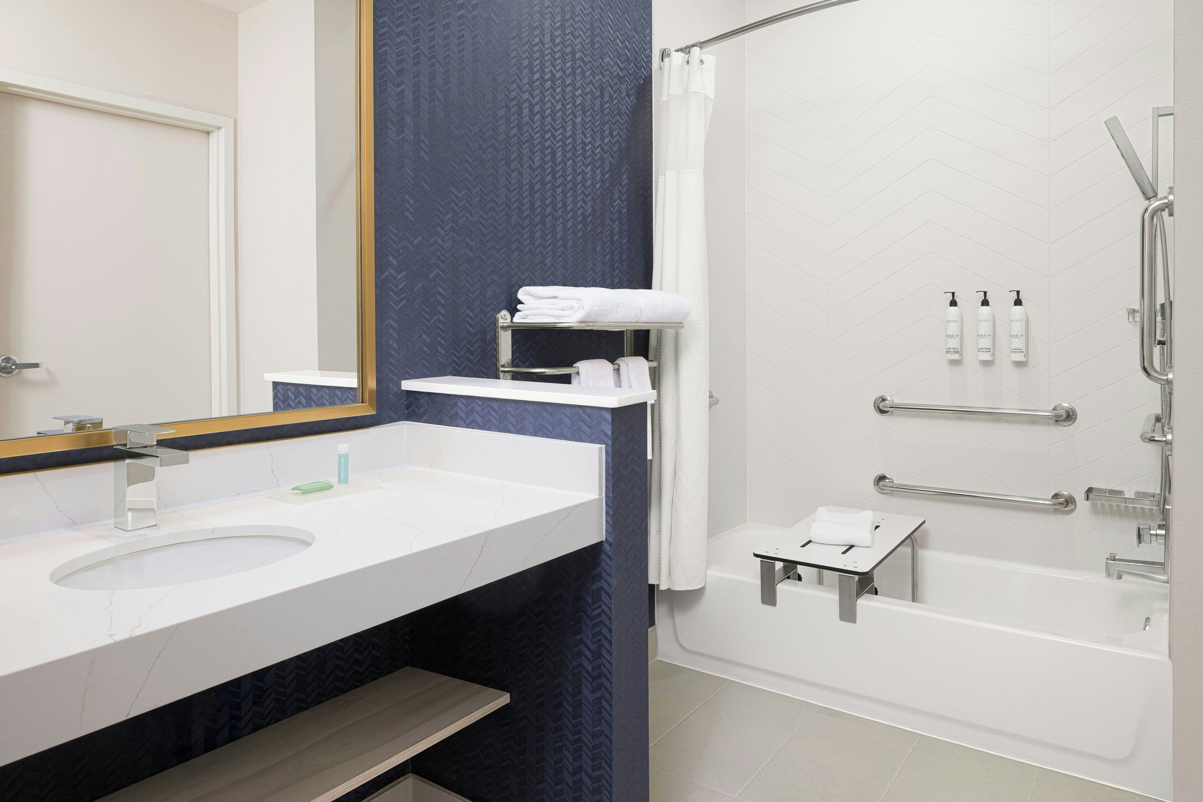 A bathroom with a white sink, mirror, and shower.