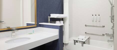 A bathroom with a white sink, mirror, and shower.