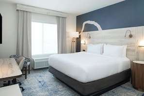 A hotel room with a large bed, a desk, a chair, a lamp, and a wall-mounted light fixture. - Fairfield By Marriott Inn & Suites Athens Madison (Madison)