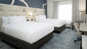 Une chambre d’hôtel avec deux lits, un bureau, une chaise et une grande fenêtre avec des rideaux.