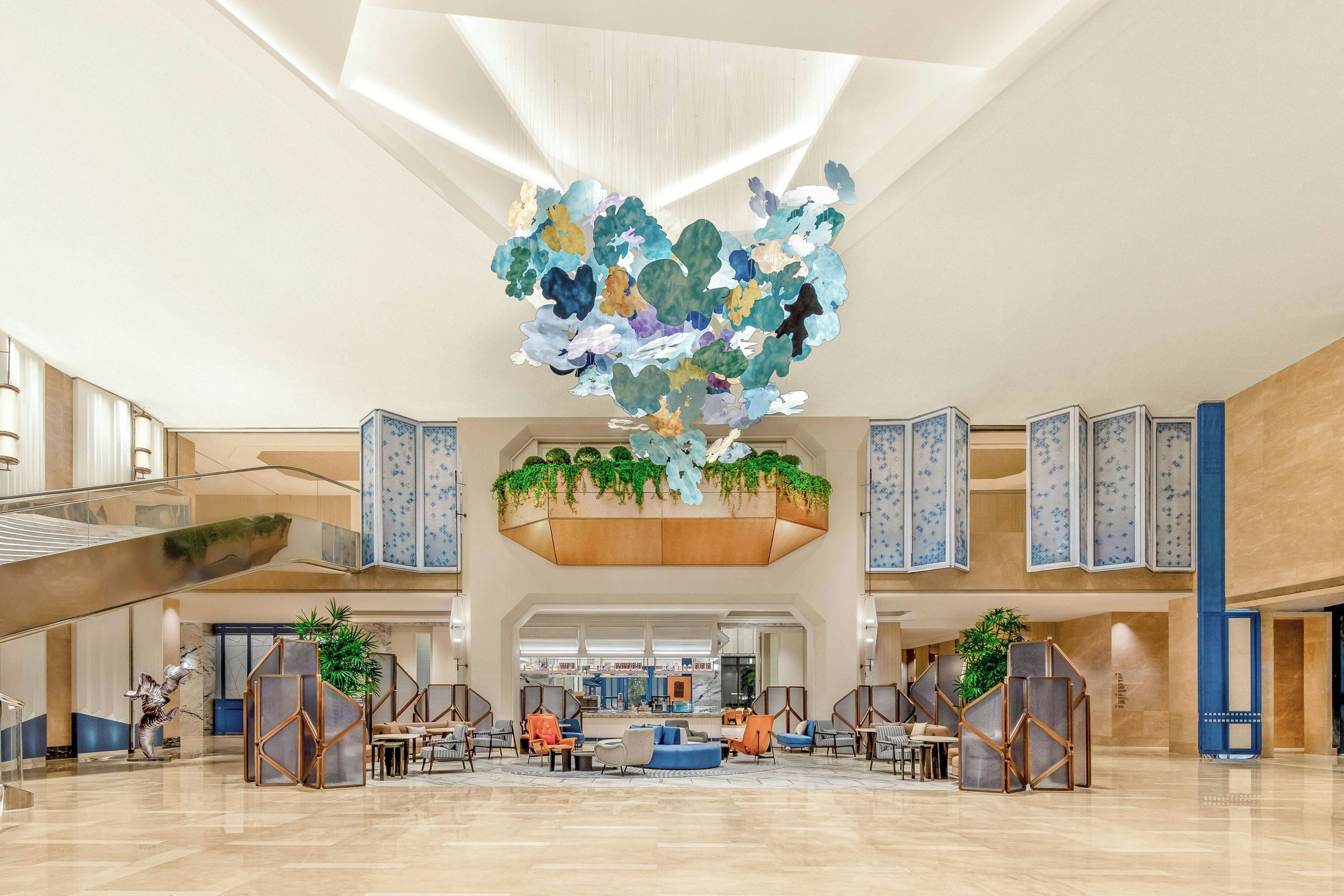 A spacious lobby with a central seating area, a staircase, and a large decorative ceiling piece.