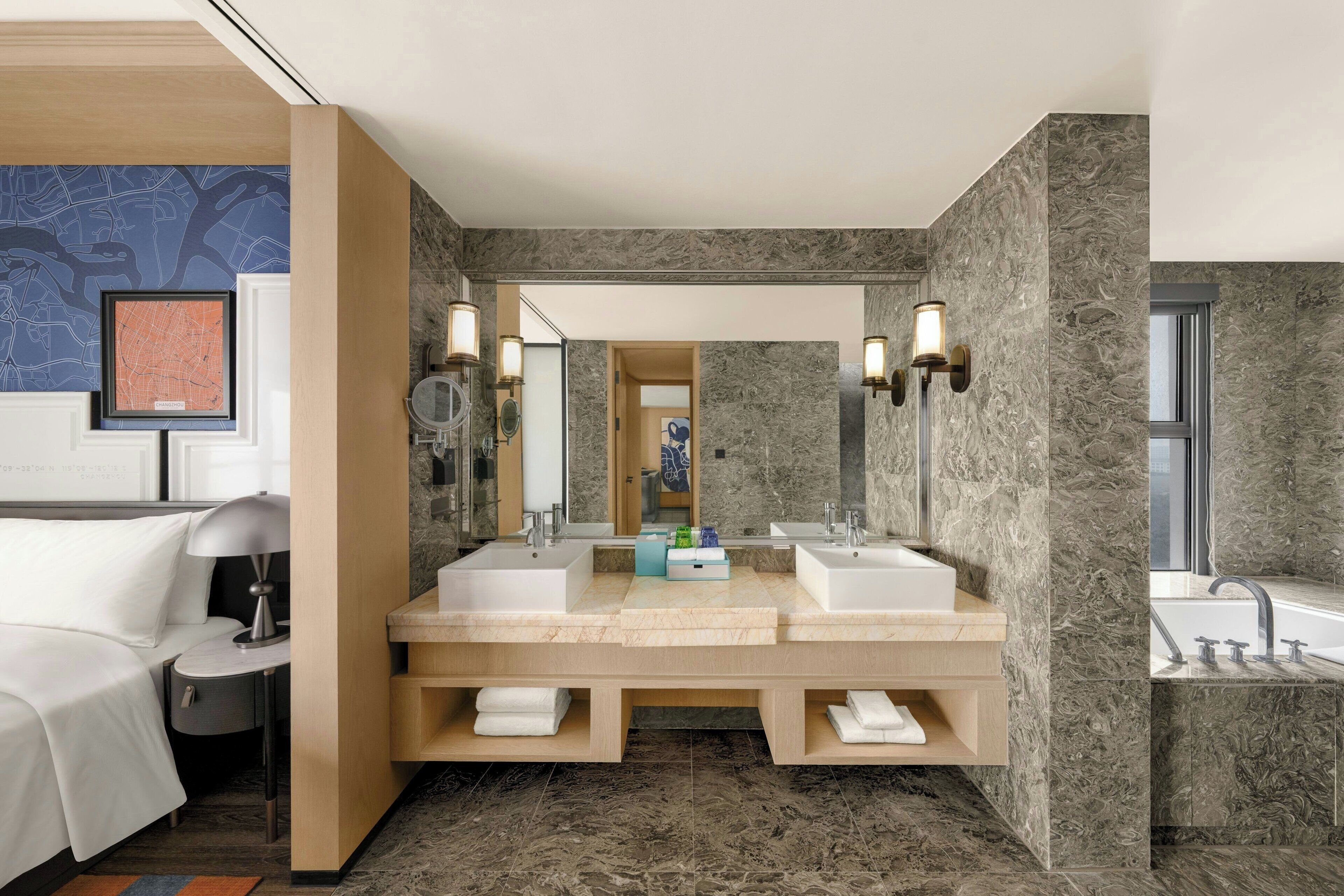 A modern bathroom with two sinks, a large mirror, and a bathtub.