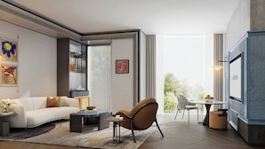 A modern living room with a sofa, armchair, coffee table, and a TV. There are artworks on the walls and a window with a view. - Le Méridien Changzhou (Changzhou)