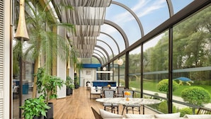 A spacious indoor area with a curved ceiling, large windows, and a dining area with chairs and tables. - Le Méridien Changzhou (Changzhou)