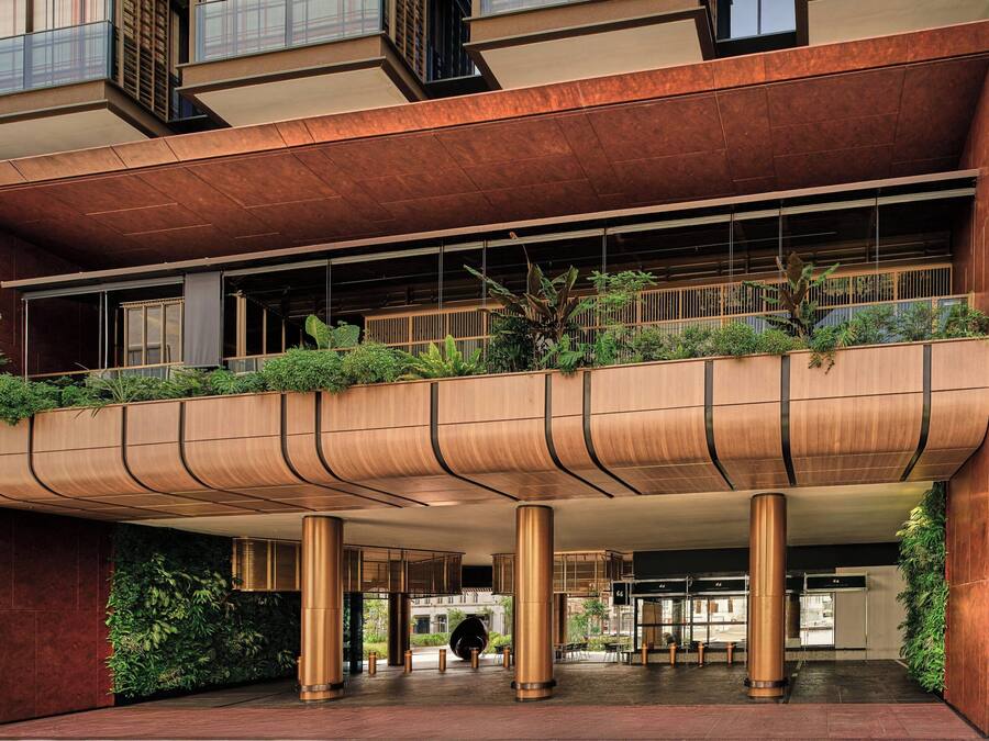 Un edificio moderno con un alero curvo, grandes pilares y un balcón con vegetación.