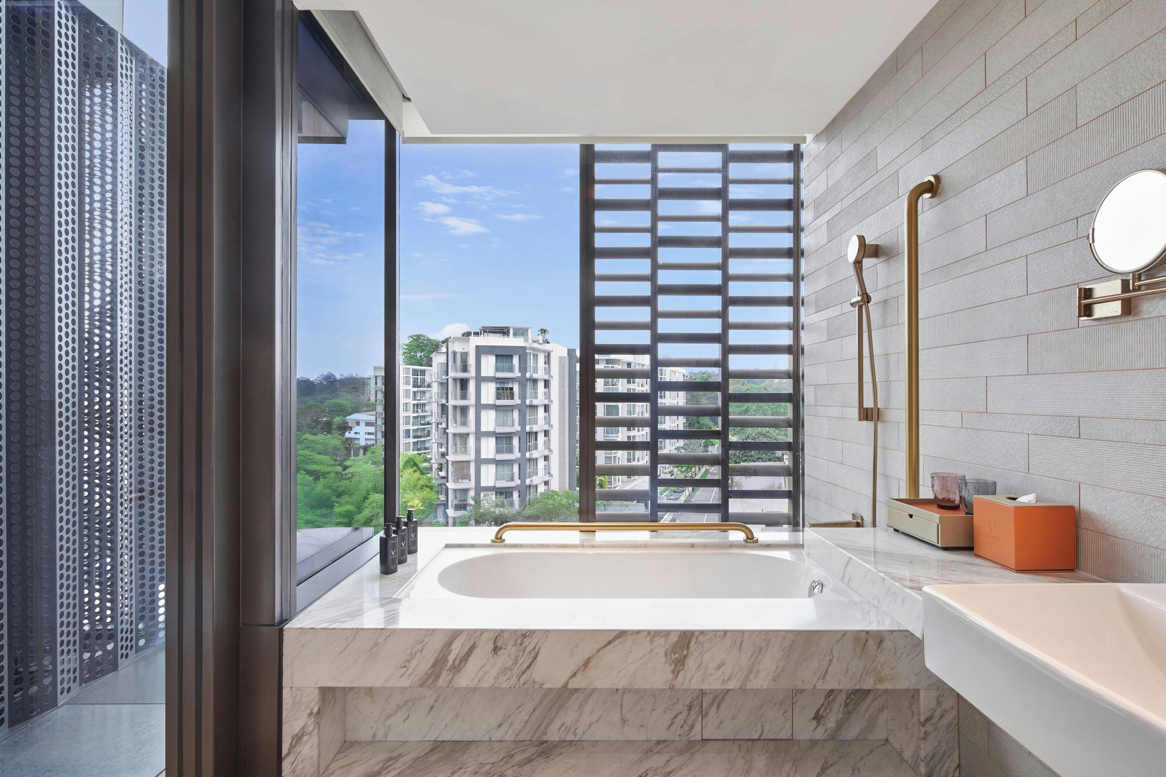 A modern bathroom with a large bathtub, a window with a view of buildings, and a shower area.