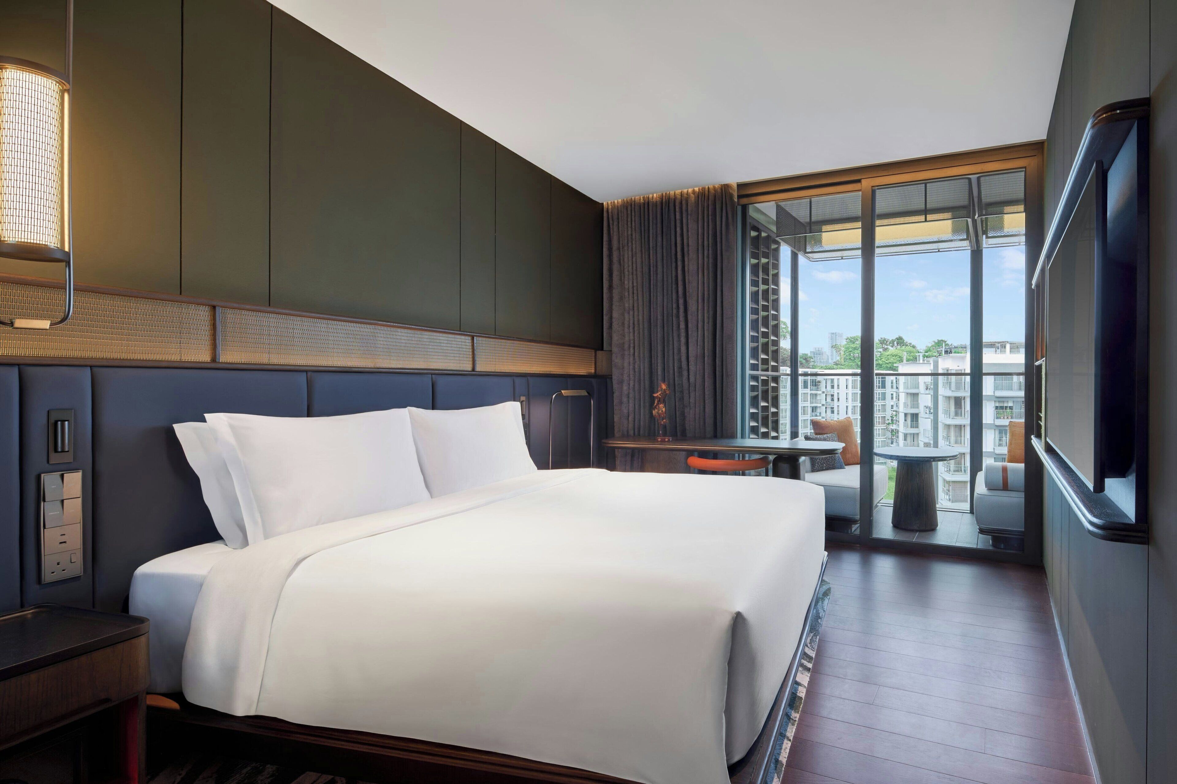 A hotel room with a large bed, a desk, and a view of the city.