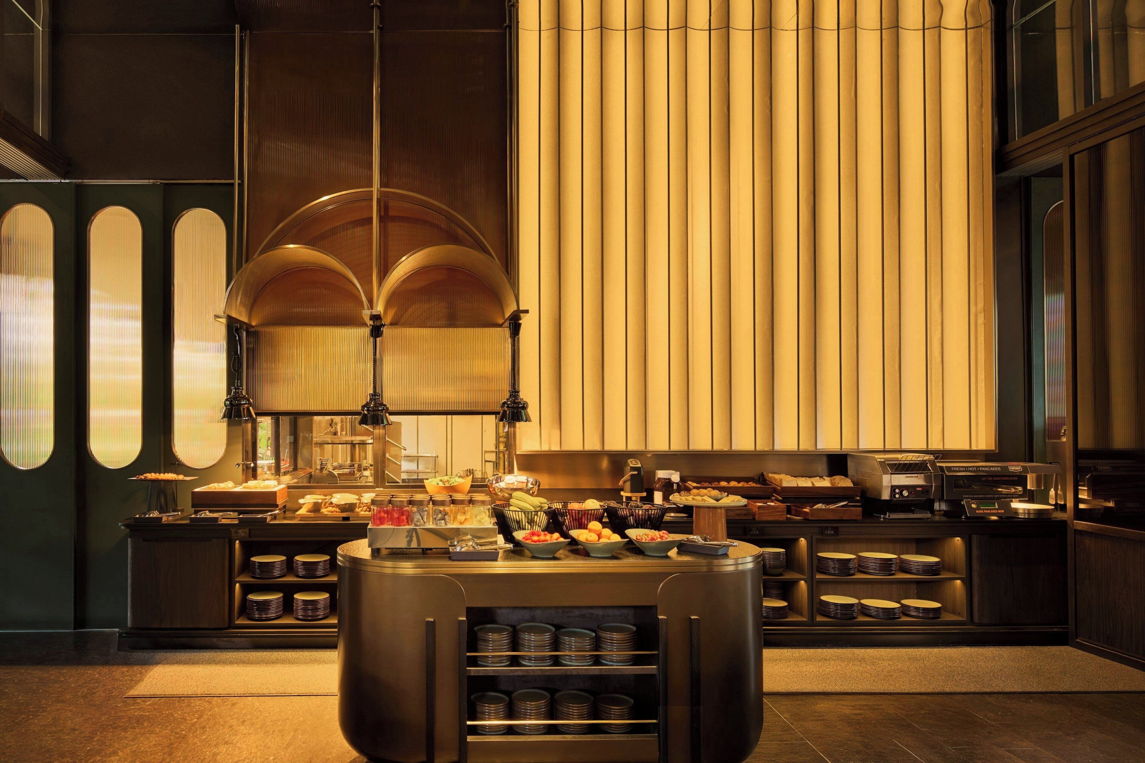 Un espai de buffet ben equipat amb diferents plats, una màquina de cafè i una àmplia zona de servei central.