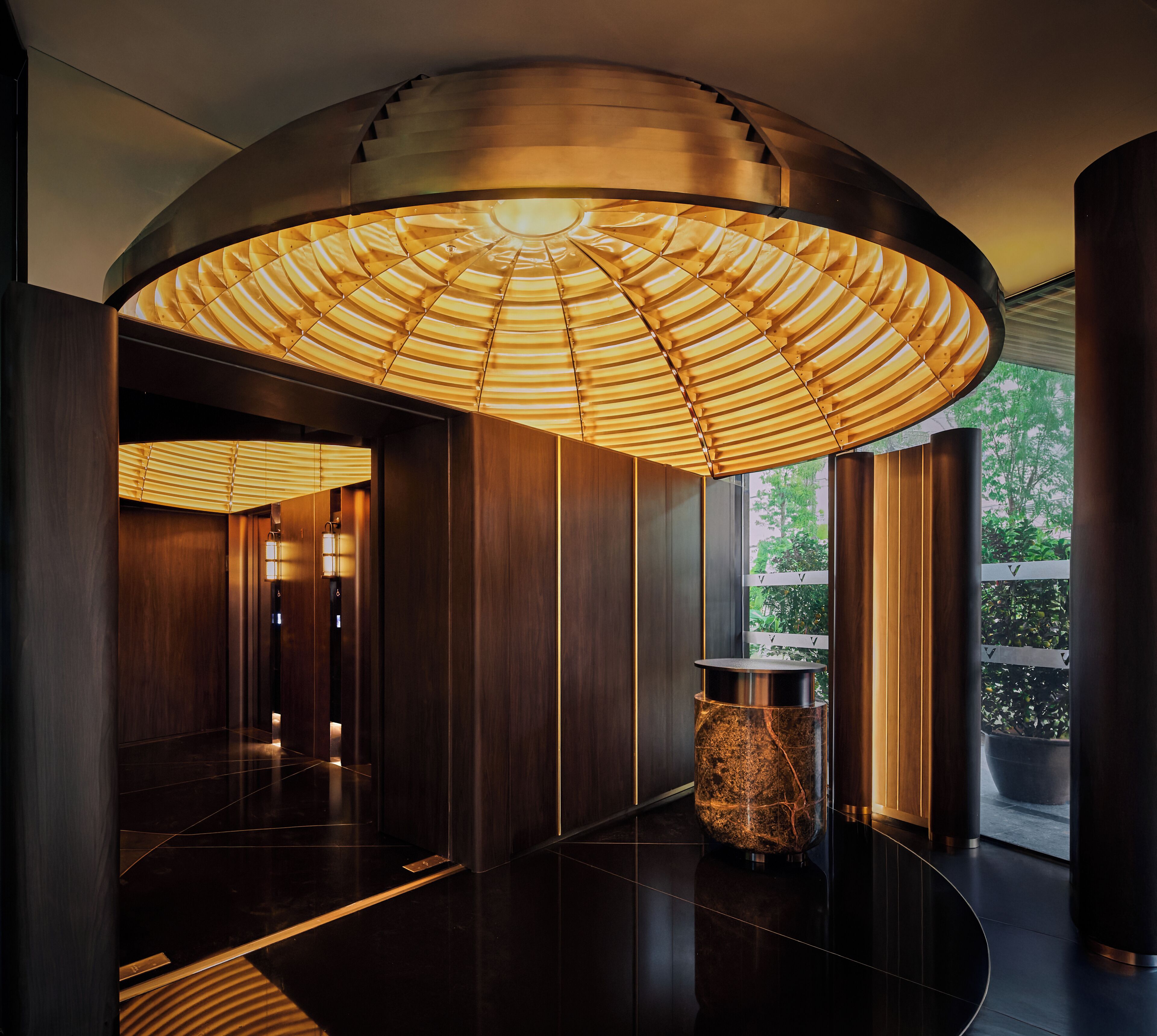 A modern interior with a curved ceiling, a central column, and a view of greenery outside.