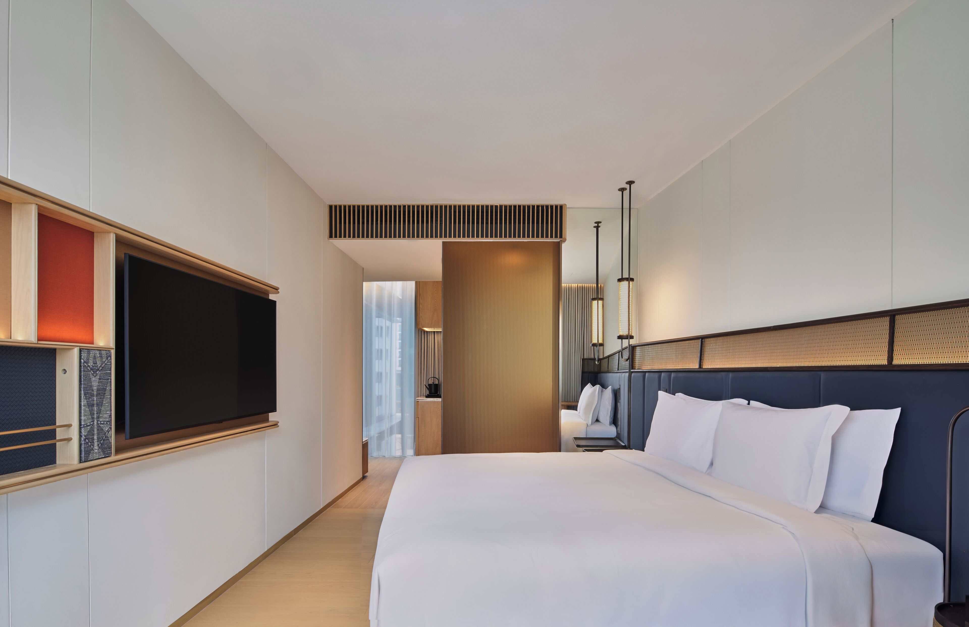 Une chambre d’hôtel moderne dotée d’un grand lit, d’un téléviseur à écran plat et offrant une vue sur la ville.