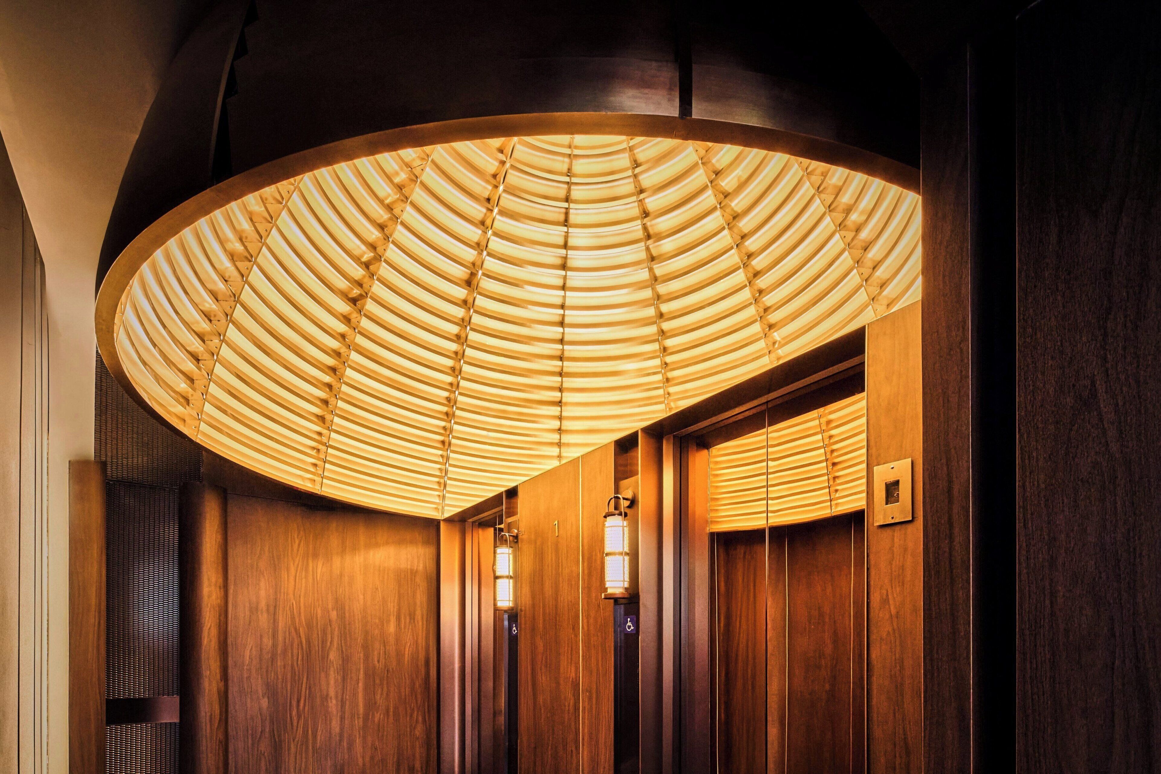 A wooden interior with a large, circular ceiling light fixture and a wall-mounted light.