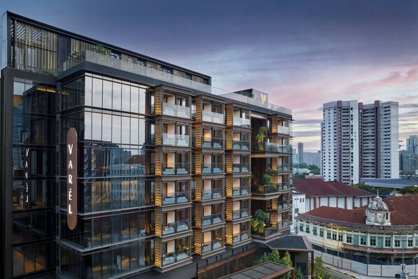 Un hôtel moderne à plusieurs étages, doté d’une façade en verre, de balcons et d’une enseigne « VAREL » bien visible.