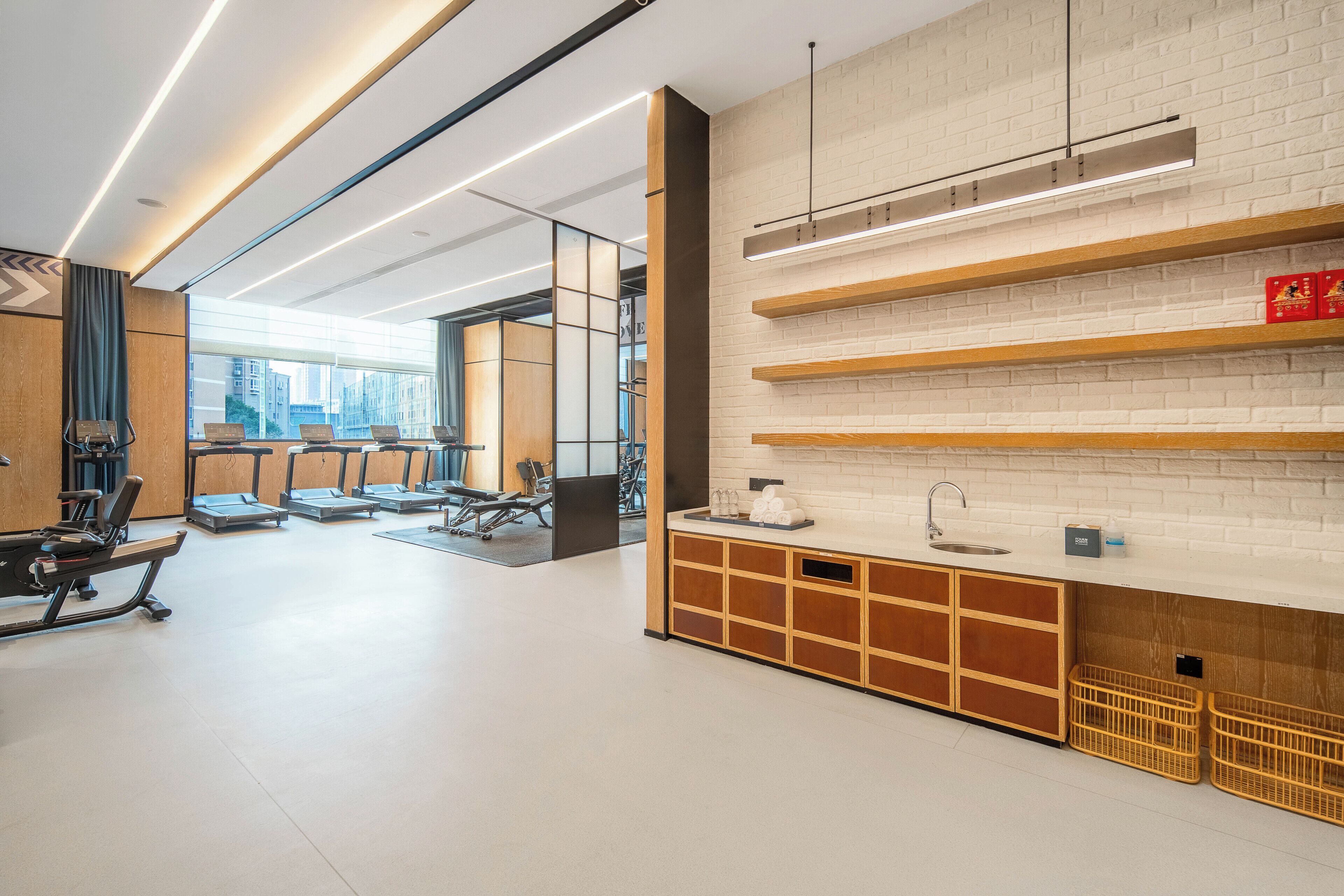 Eine moderne Hotelhalle mit Fitnessbereich, einer Rezeption und einem großen Fenster mit Blick auf die Stadt.