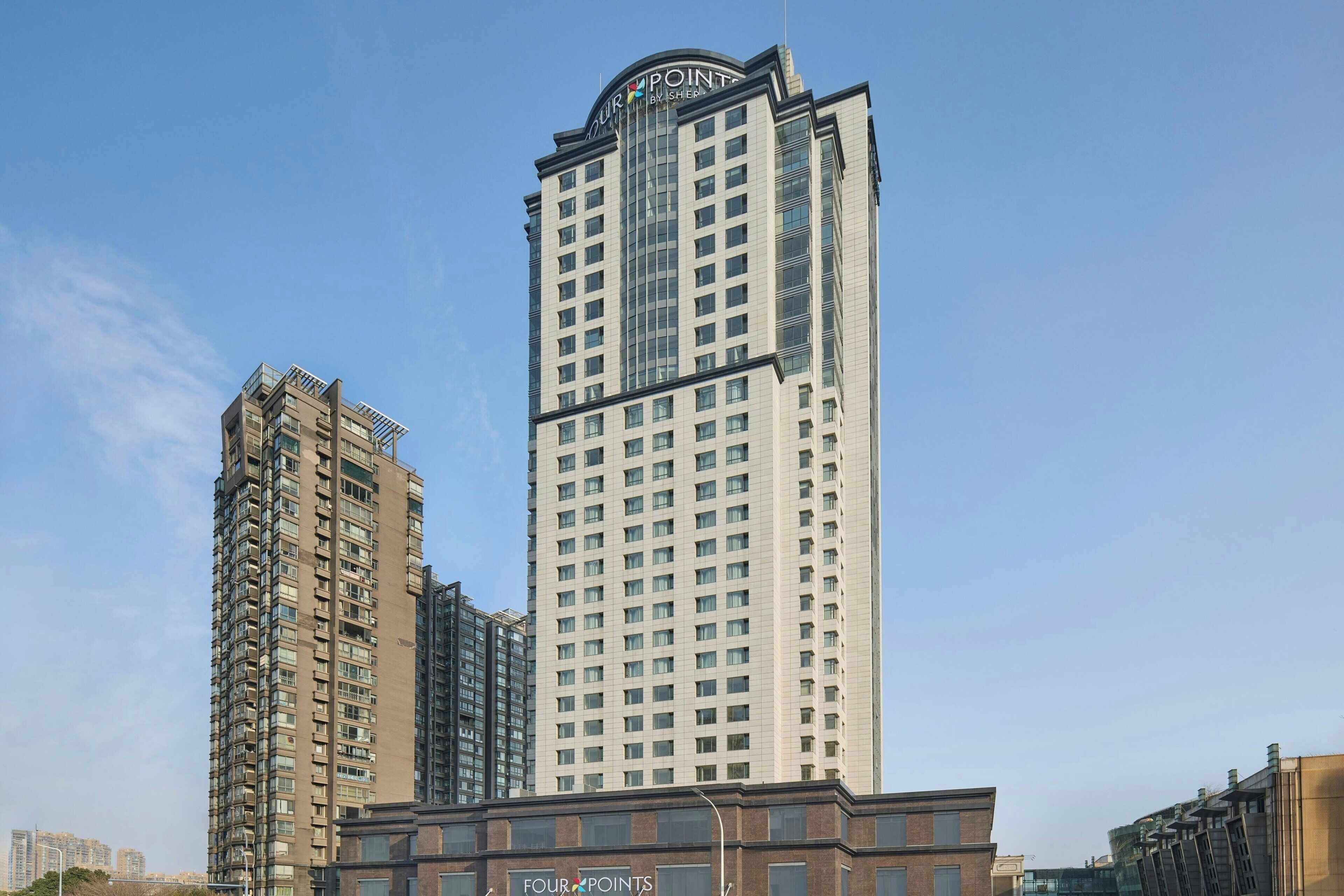 A high-rise hotel with a prominent 'Four Points' sign, multiple floors, and a modern architectural design.
