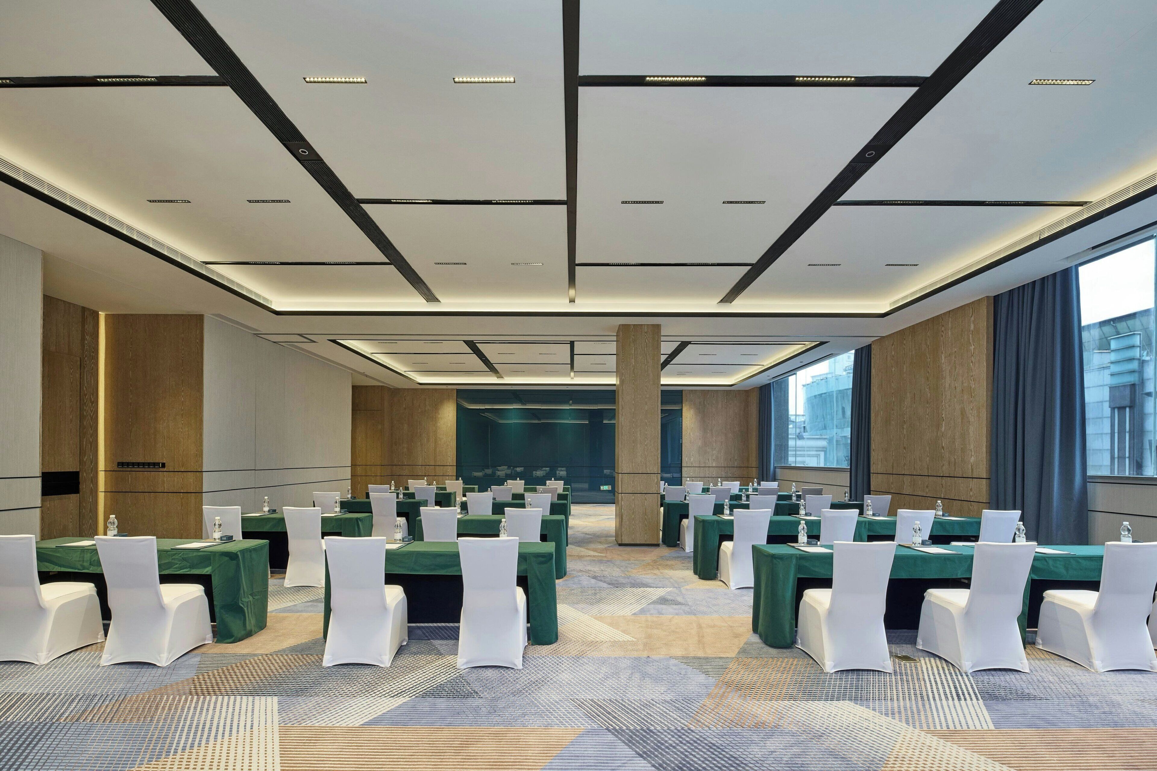 A conference room with multiple tables, white chairs, and a patterned carpet.