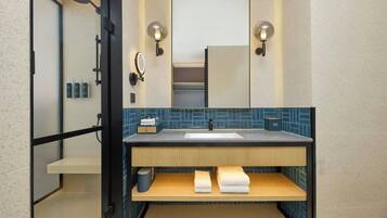 A modern bathroom with a shower, a sink, a mirror, and a towel rack.