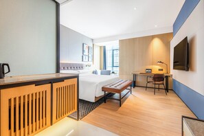 Una habitación de hotel moderna con cama, escritorio, silla y televisión.