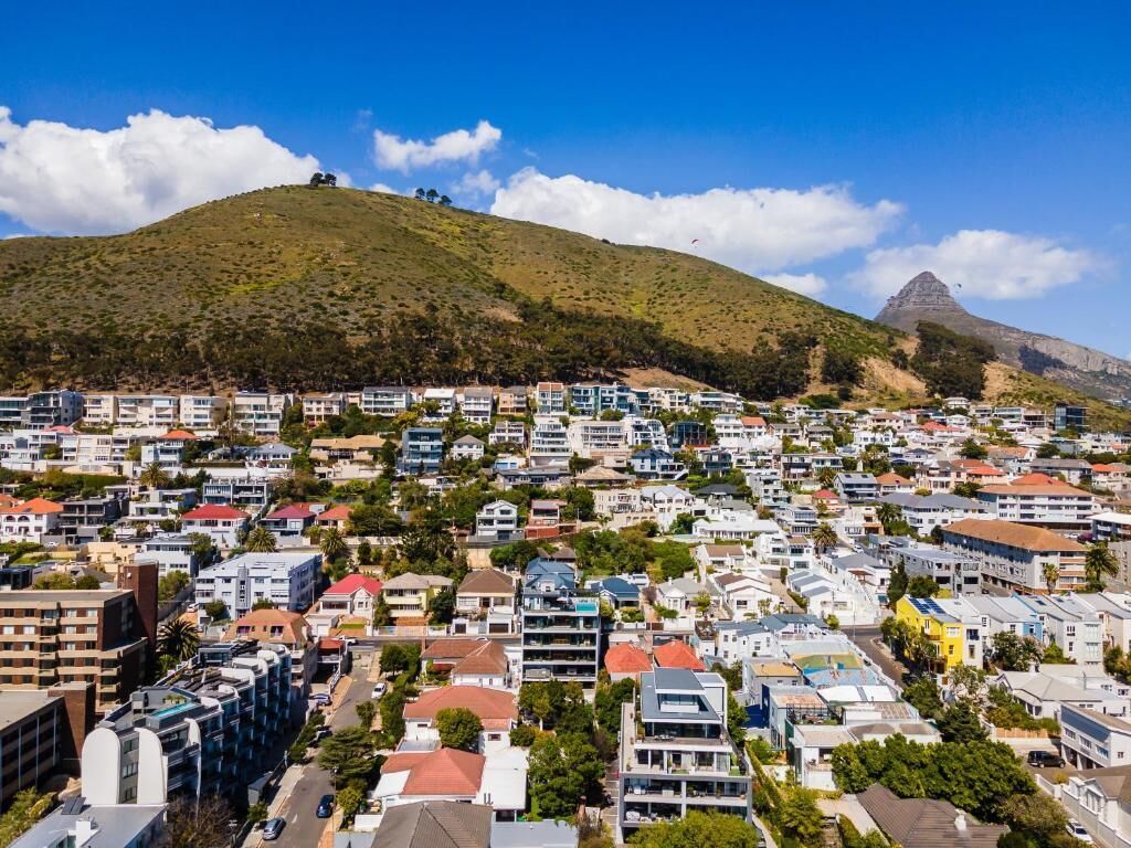 A residential area with a hill in the background and a prominent mountain peak.