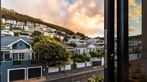 Un quartier résidentiel avec des maisons construites sur une colline, une rue et une vue à travers une fenêtre.
