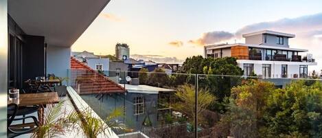 Apartamento moderno com varanda e vista para a cidade ao pôr do sol.