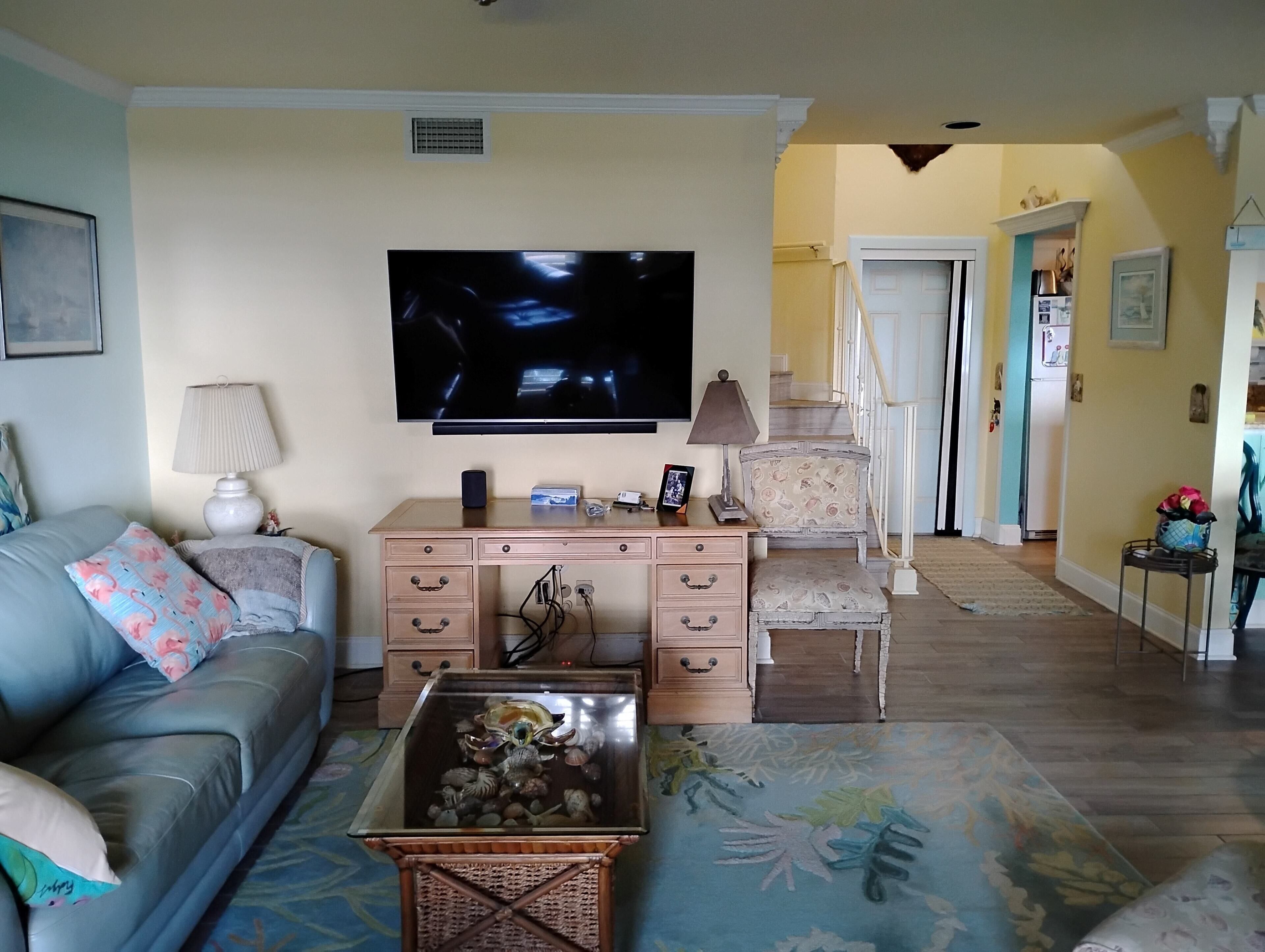 A living room with a sofa, a coffee table with decorative items, a TV, a desk with drawers, and a chair.