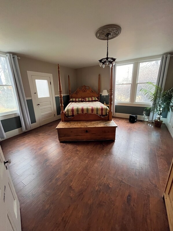 A bedroom with a four-poster bed, a ceiling fan, and large windows.