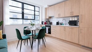 A modern kitchen with wooden cabinets, a dining table with chairs, and a large window.