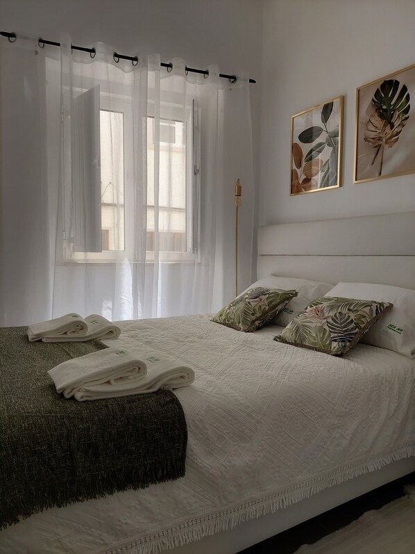 A neatly made bed with a white comforter, two pillows with tropical leaf patterns, and folded towels on the bed. - SEA AIR Local Accommodations - Beachfront Location and Comfort All in One Place (Nazaré)